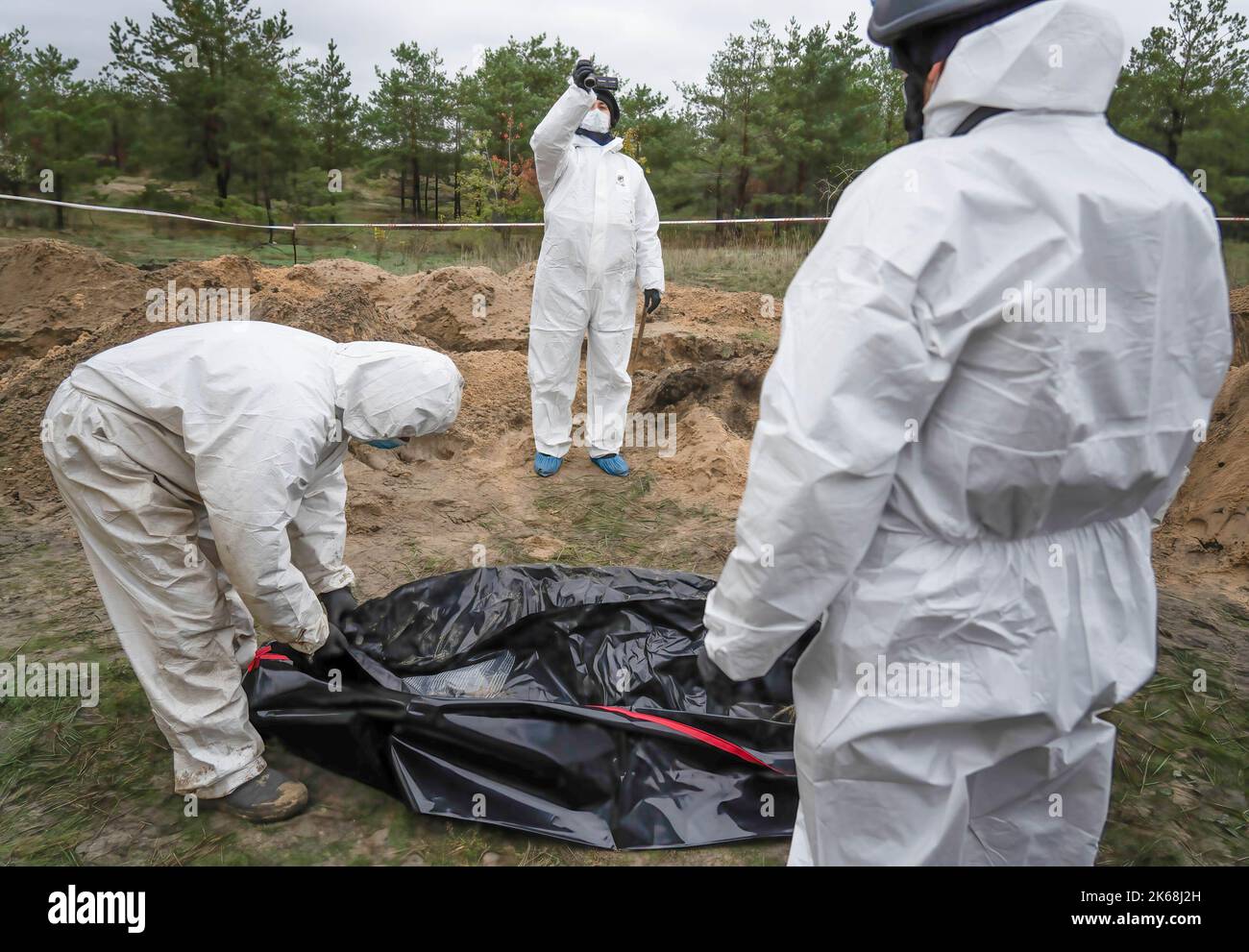 Investigators are seen zipping a body bag carrying an exhumed body in Lyman. At least 32 Ukrainian soldiers' bodies have been exhumed from a mass grave in Lyman, a city in Donetsk region that was under Russian occupation. Authorities said they were buried together and initial investigation has shown some bodies were blindfolded and tied on the hands, which suggested signs of torture and execution. Another 22 civilians, including children were exhumed from another burial site nearby. Both sites located at the edge of a cemetery. Officials said they are expecting more bodies to be found. (Photo Stock Photo