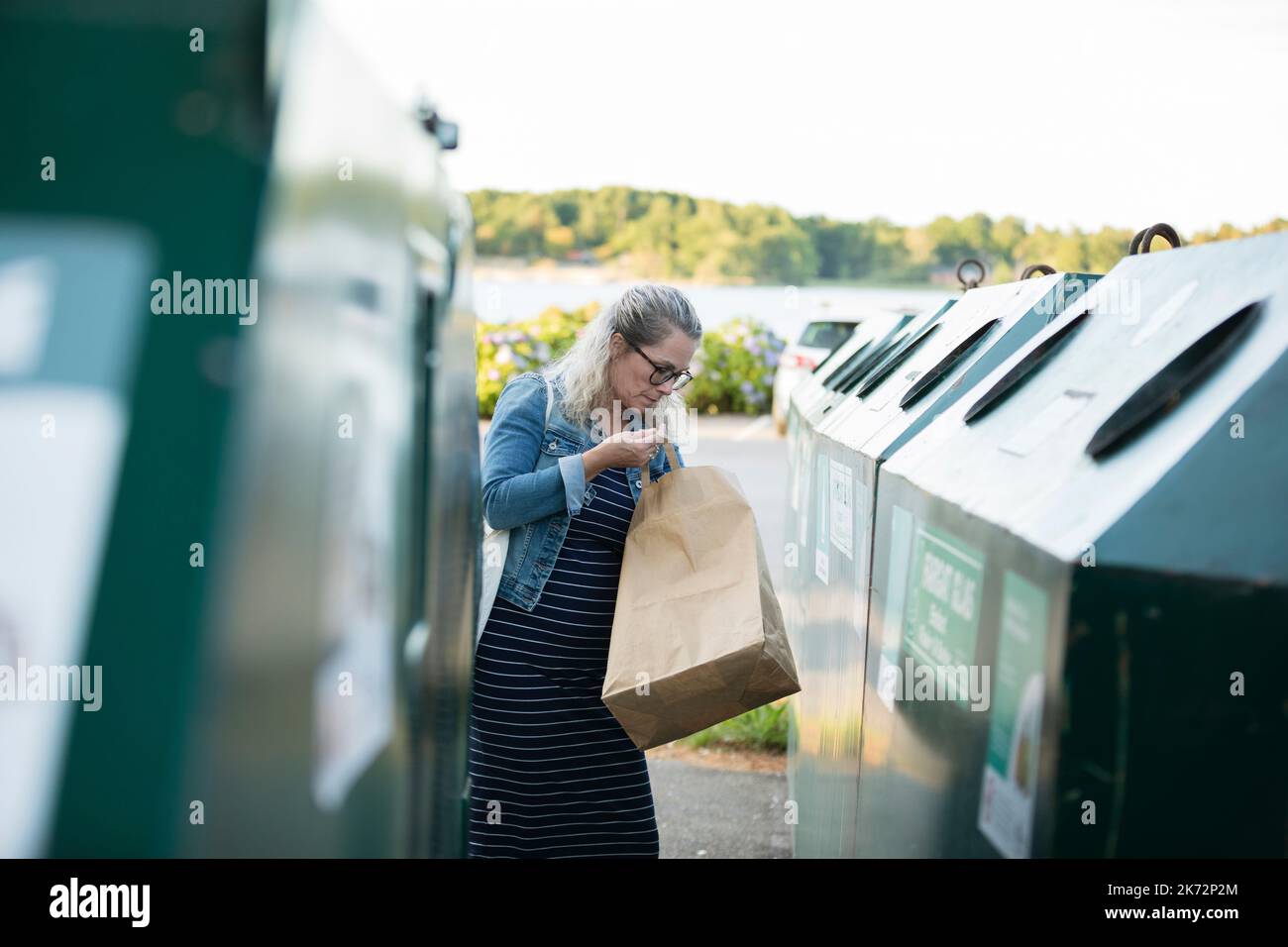 Blond woman throwing rubbish into waste bin Stock Photo