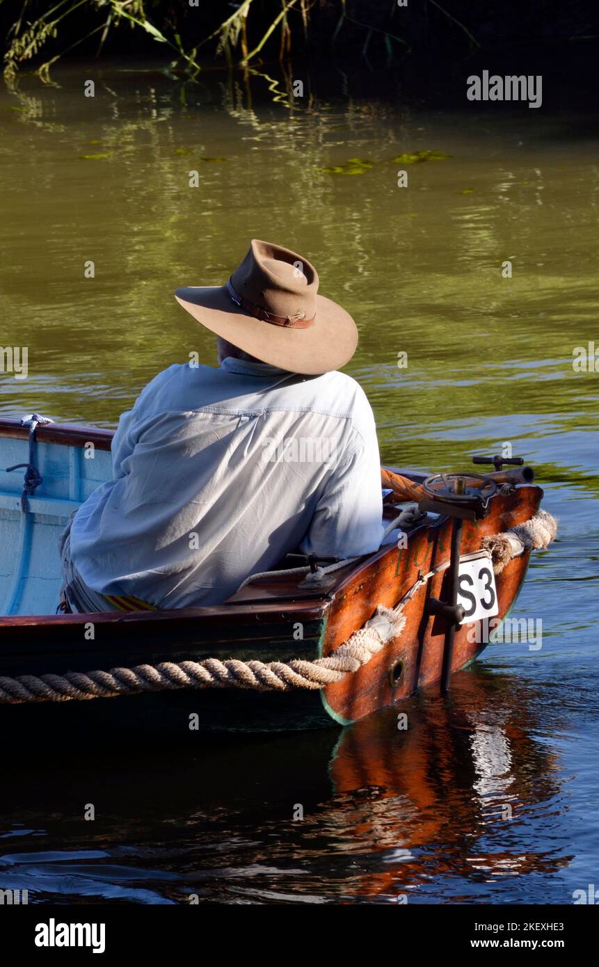 solitary man in sunhot in vintage wooden clinker built old fashioned boat an river waveney at geldeston norfolk england Stock Photo