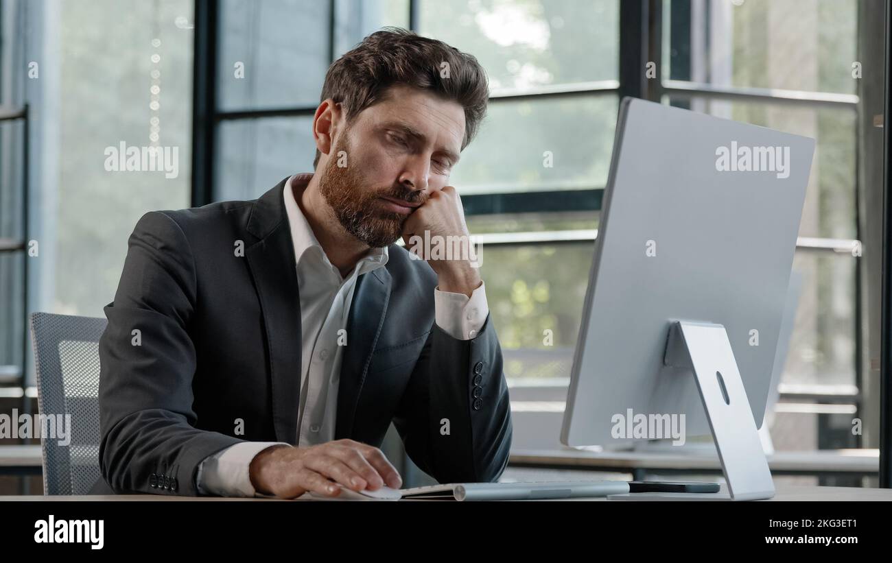 Sleeping tired lazy napping yawn adult bearded man male manager worker bored at work project online in computer in office Caucasian mature ill Stock Photo