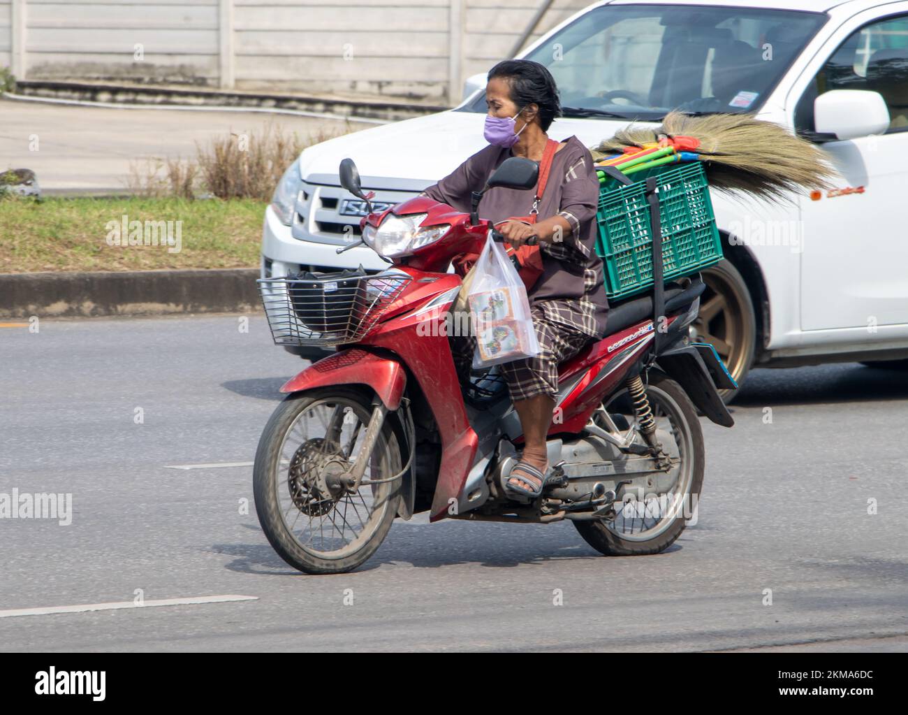 RATCHABURI, THAILAND, NOV 16 2022, Women ride a motorbike with a load of brooms Stock Photo