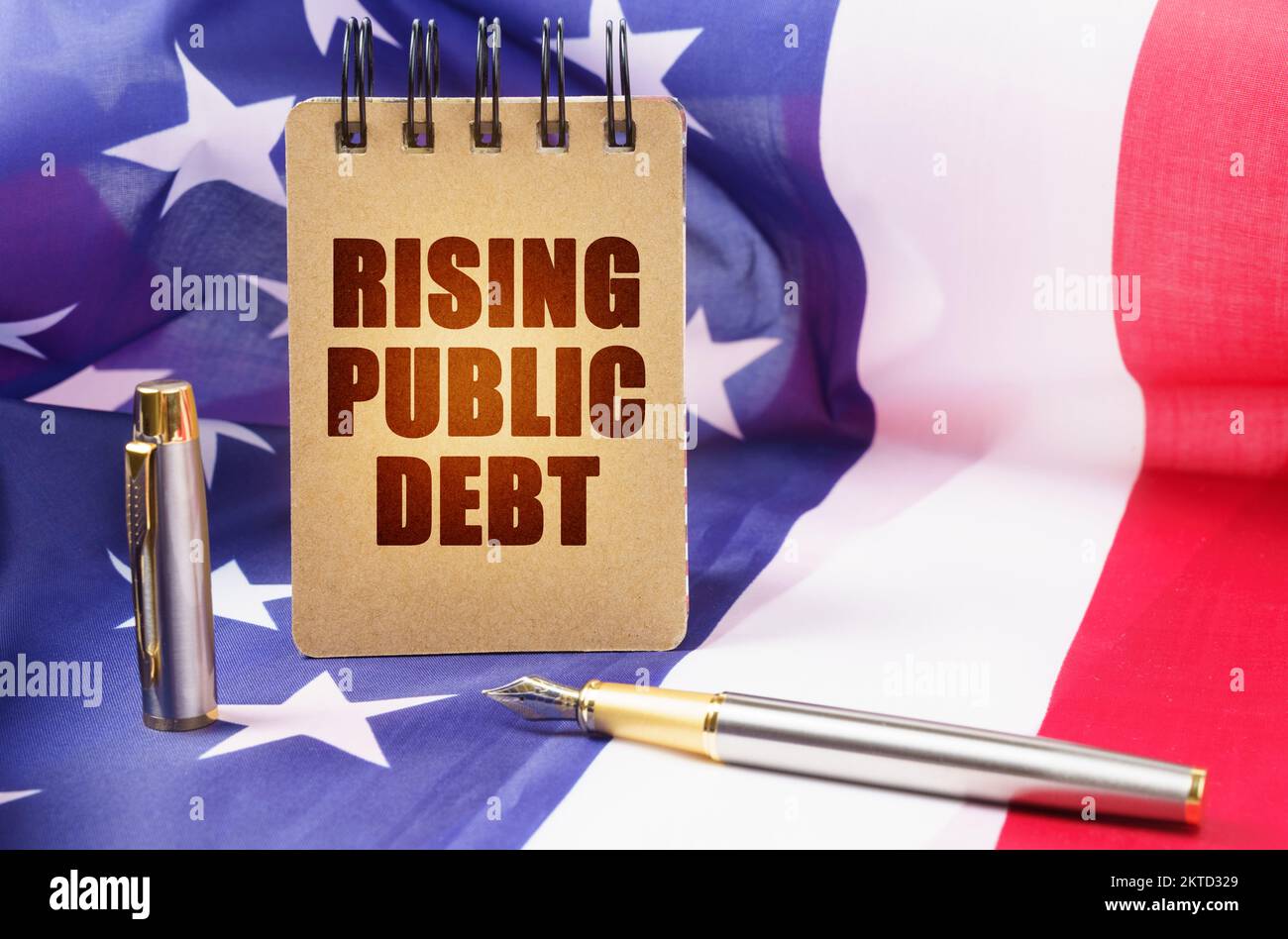 Business concept. Against the background of the American flag is a notepad with the inscription - rising public debt Stock Photo