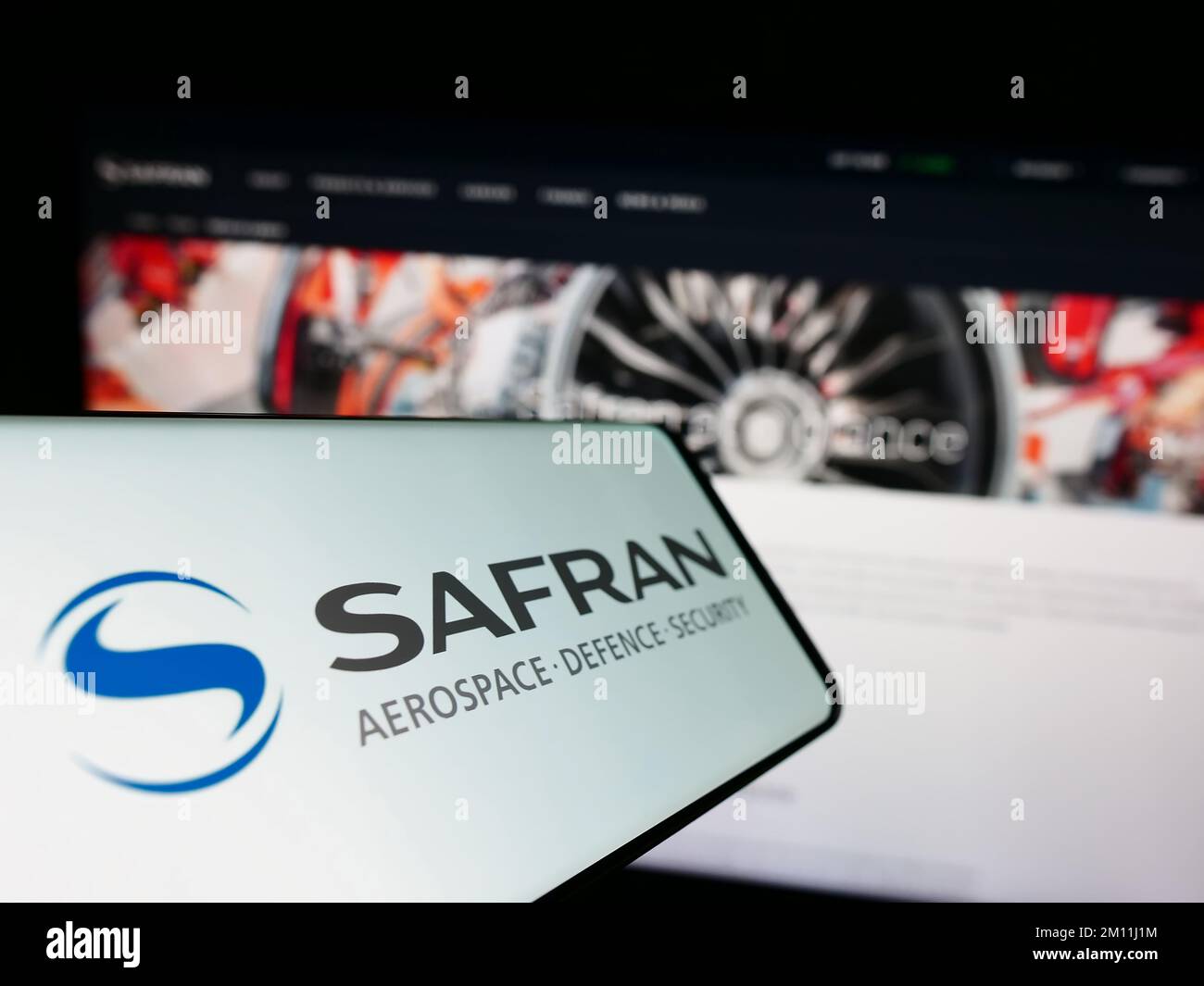 Cellphone with logo of French aerospace company Safran S.A. on screen in front of business website. Focus on center-left of phone display. Stock Photo