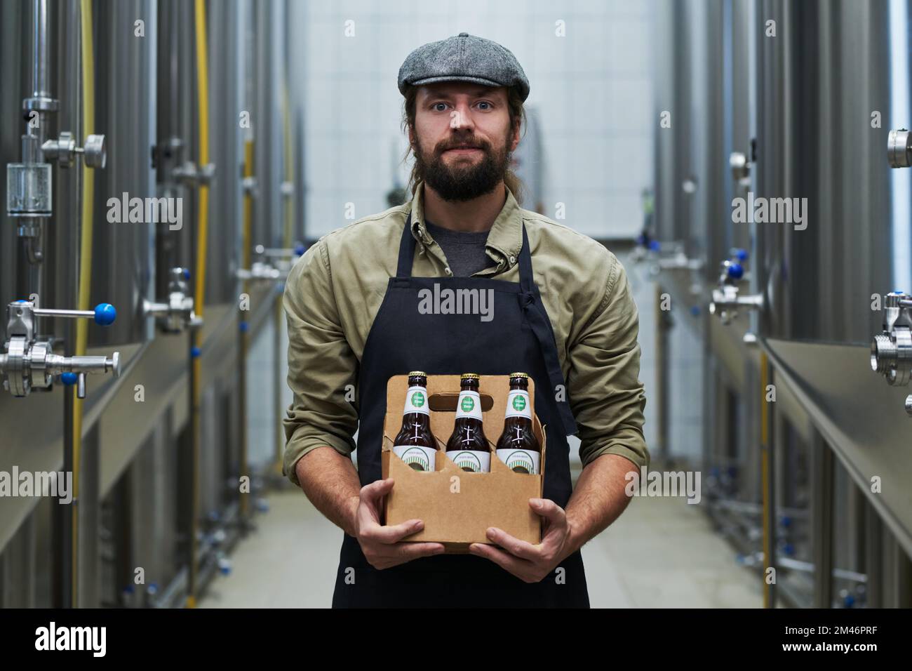 Portrait of positive brewery owner holding six pack of beer Stock Photo