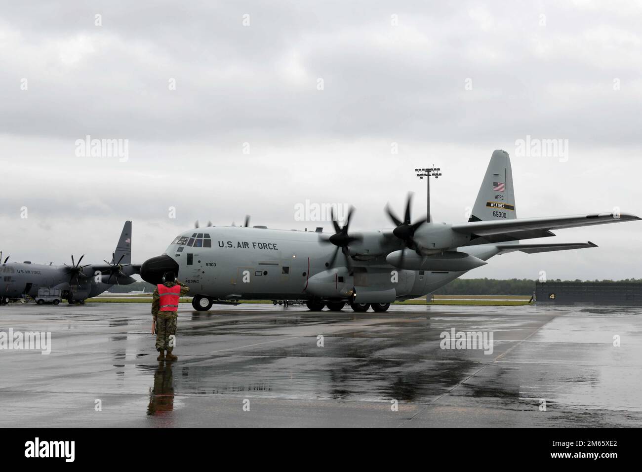 ROBINS AIR FORCE BASE,Ga. – Airman 1st Class Marcos Parada, 146th Airlift Wing crew chief from the California Air National Guard, salutes a WC-130J aircraft at Robins Air Force Base, Georgia, April 5, 2022, as it leaves for Keesler Air Force Base, Mississippi. While at the Warner Robins Air Logistics Complex at Robins AFB, the aircraft received a new glossy gray paint scheme known for its durabilty, longevity and efficiency under harsh weather conditions reminescient of its days prior to 2008. Stock Photo