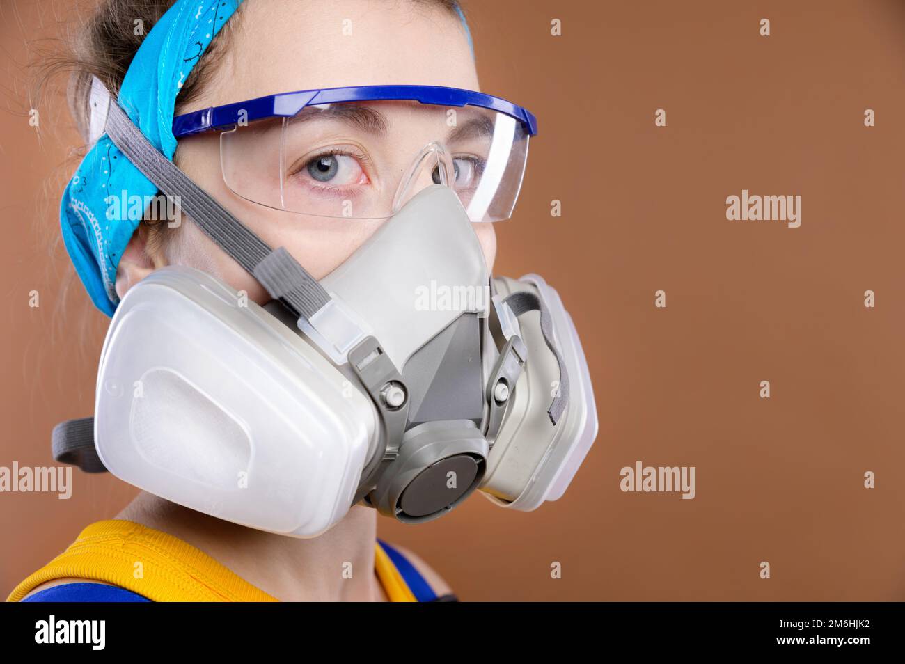 Portrait of a young Caucasian woman in protective equipment for the organs of vision and respiration. Look into the camera. A gi Stock Photo