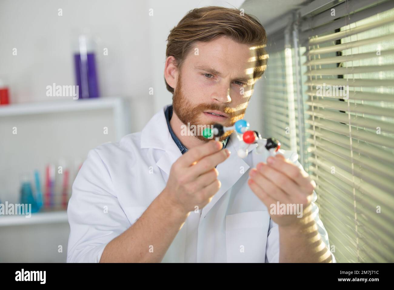 researcher with a white lab coat holding a molecular model Stock Photo