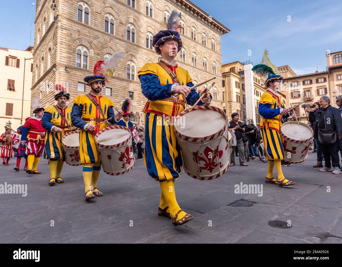 A parade of men dressed in period costumes march into the Piazza Della Signori while playing their drums decorated in the coat of arms of Florence Stock Photo