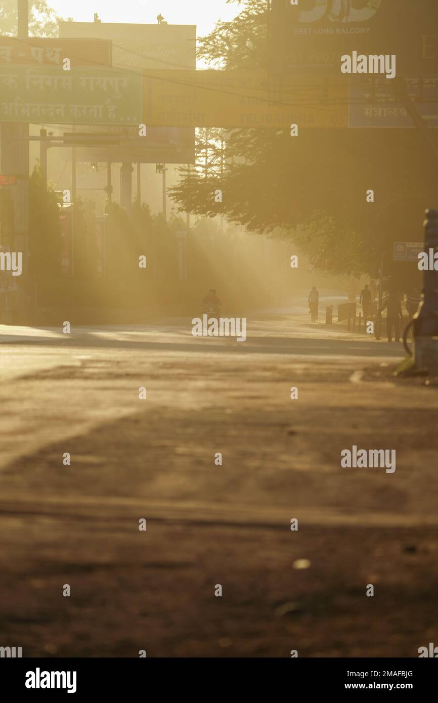 Beautiful empty road early morning sun light passing through tress in raipur, people with bicycle at morning, early morning of raipur, chhattisgarh, s Stock Photo