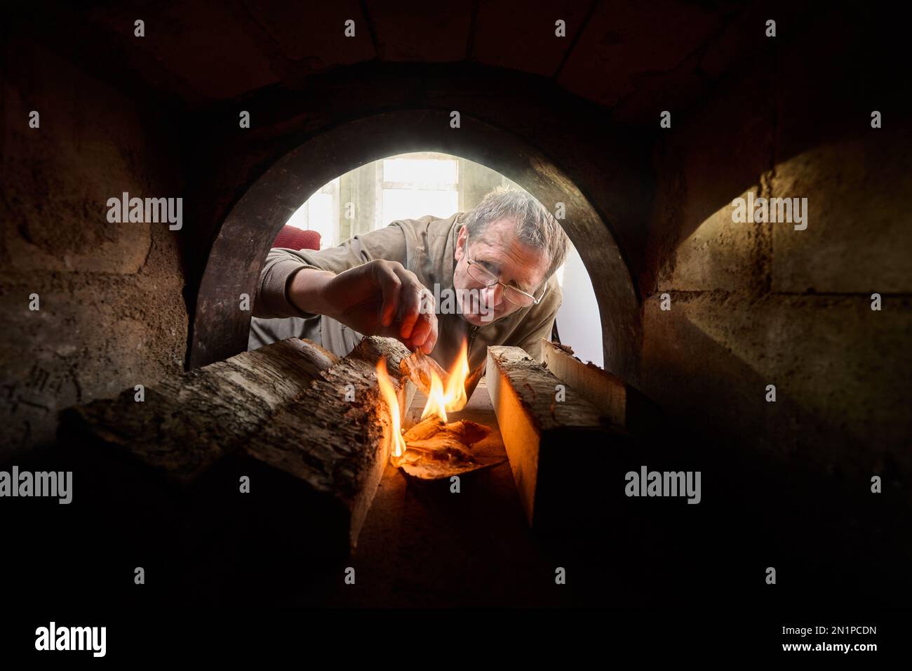 Firebox of stone wood burning stove in which fire is made to heat home. Stock Photo