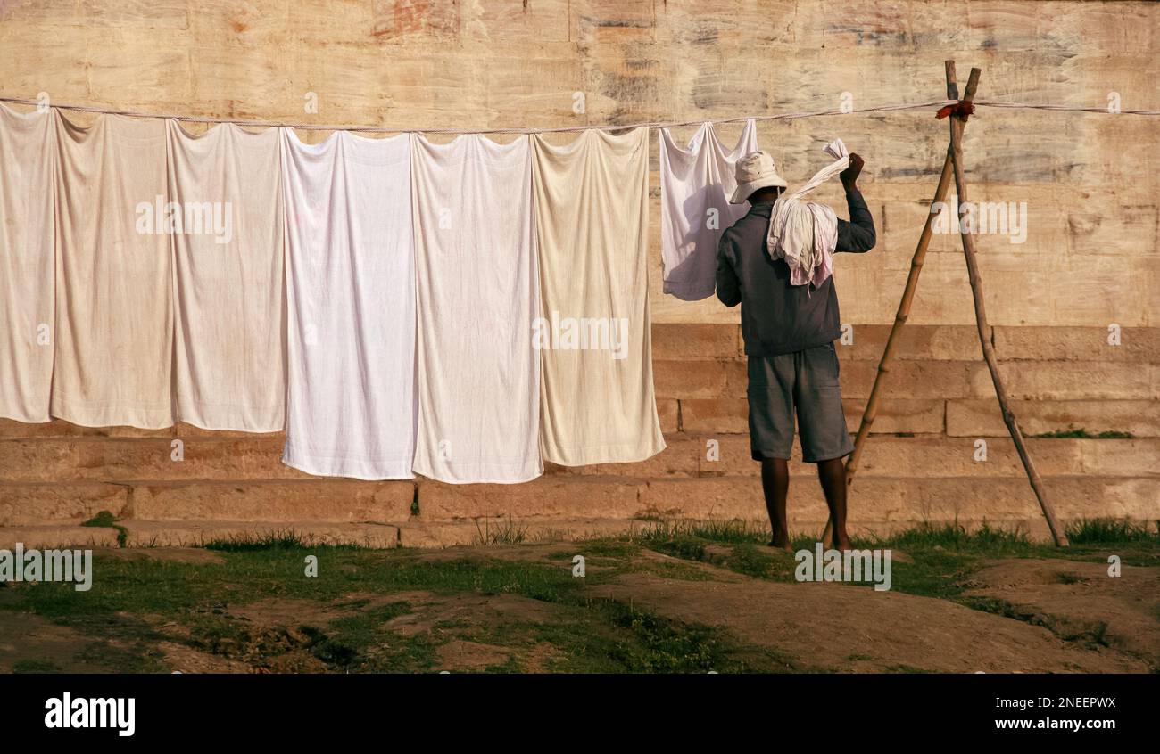 Adult Indian man facing away working doing an everyday job, hanging out washing on a line in the sun Stock Photo