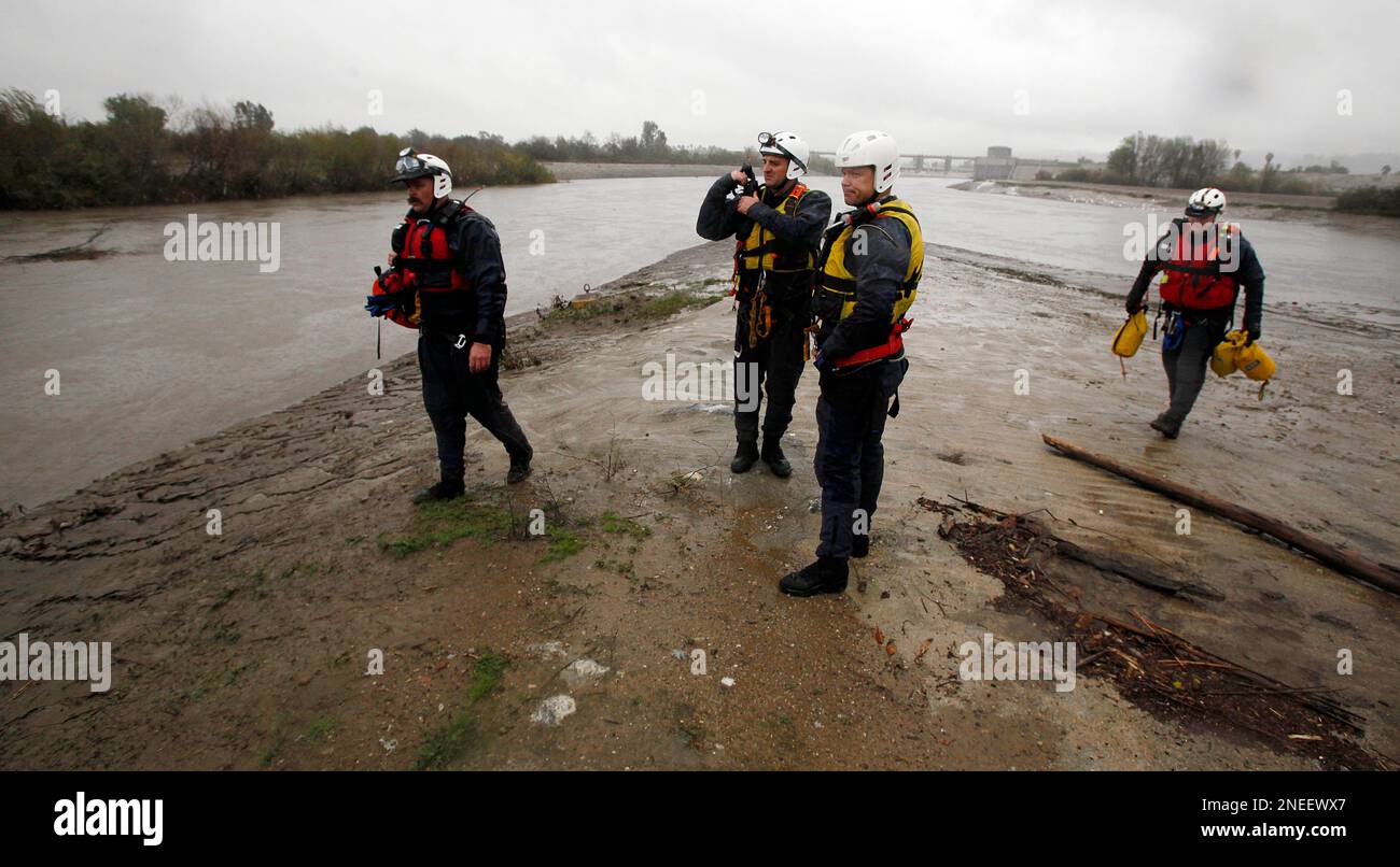 This Jan. 21, 2010 photo shows members of the Los Angeles City Fire Department's swift water rescue team, from left, Dusty Clark, Capt. Craig White, David Danielson and Dan Arnold, surveying water behind the Sepulveda Dam flood control basin, which controls the upper reaches of the Los Angeles River in the San Fernando Valley, in a demonstration of tactics. A series of storms has dropped several inches of rain, swelling rivers, creeks, flood control channels and even low-lying roads and freeways. In the latest storms, swift water rescue teams have plucked drivers off the roofs of flooded cars, Stock Photo