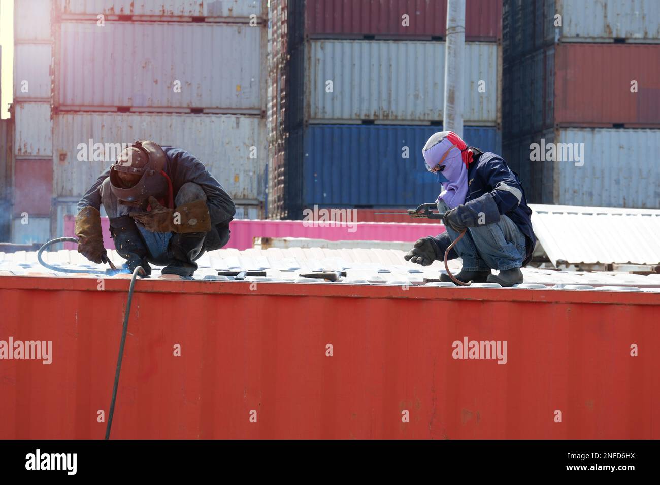 Workers repair damaged container walls Industry at the welding plant is closed. Stock Photo