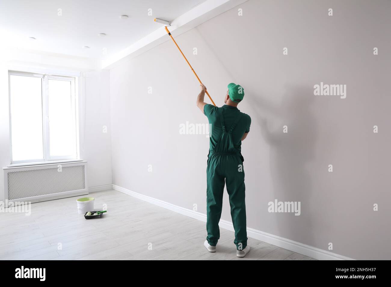 Man painting ceiling with roller in room, back view Stock Photo - Alamy