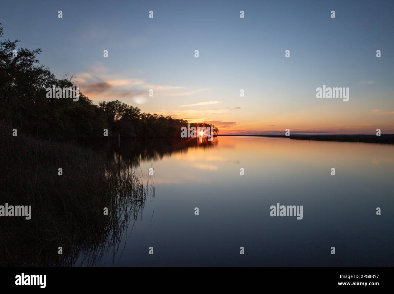 As the sun dipped below the horizon, the bay was transformed into a breathtaking scene of tranquility, casting a serene and awe-inspiring glow. Stock Photo