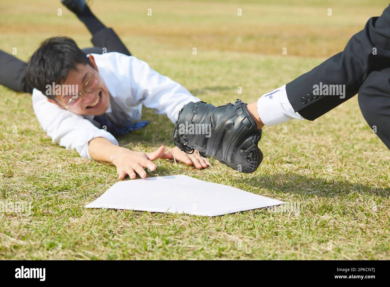 Man in suit sliding into home base Stock Photo