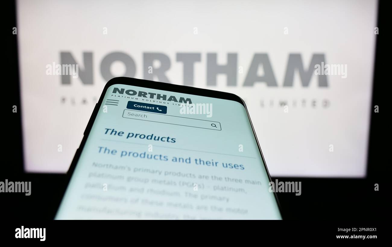 Mobile phone with webpage of company Northam Platinum Holdings Limited on screen in front of business logo. Focus on top-left of phone display. Stock Photo