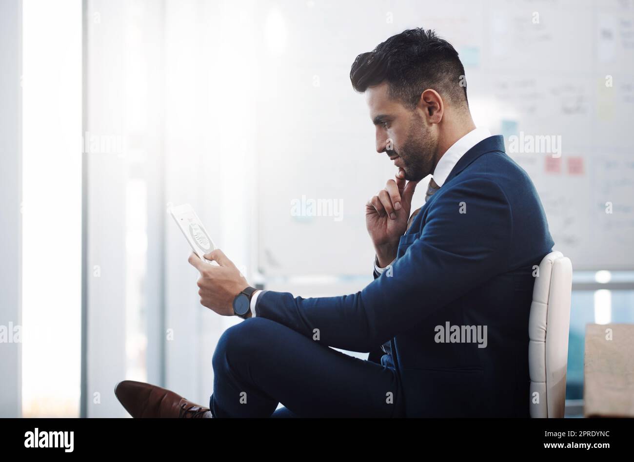 Smart apps have been supporting his career success. a young businessman working on a digital tablet in an office. Stock Photo