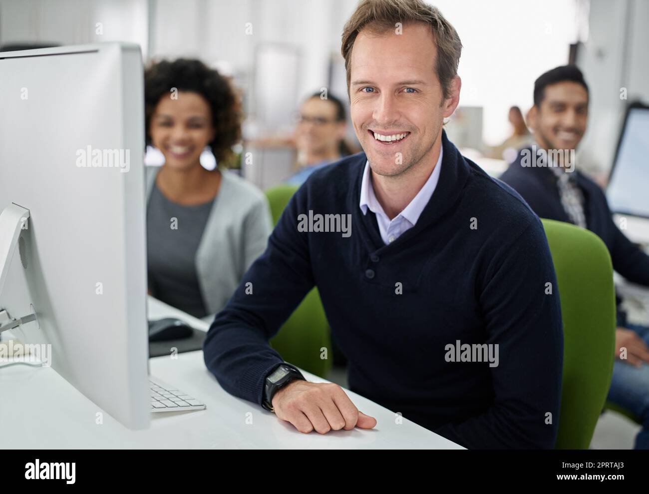 Our work space has a positive attitude. Portrait of a businessman smiling with his co-workers in the background. Stock Photo