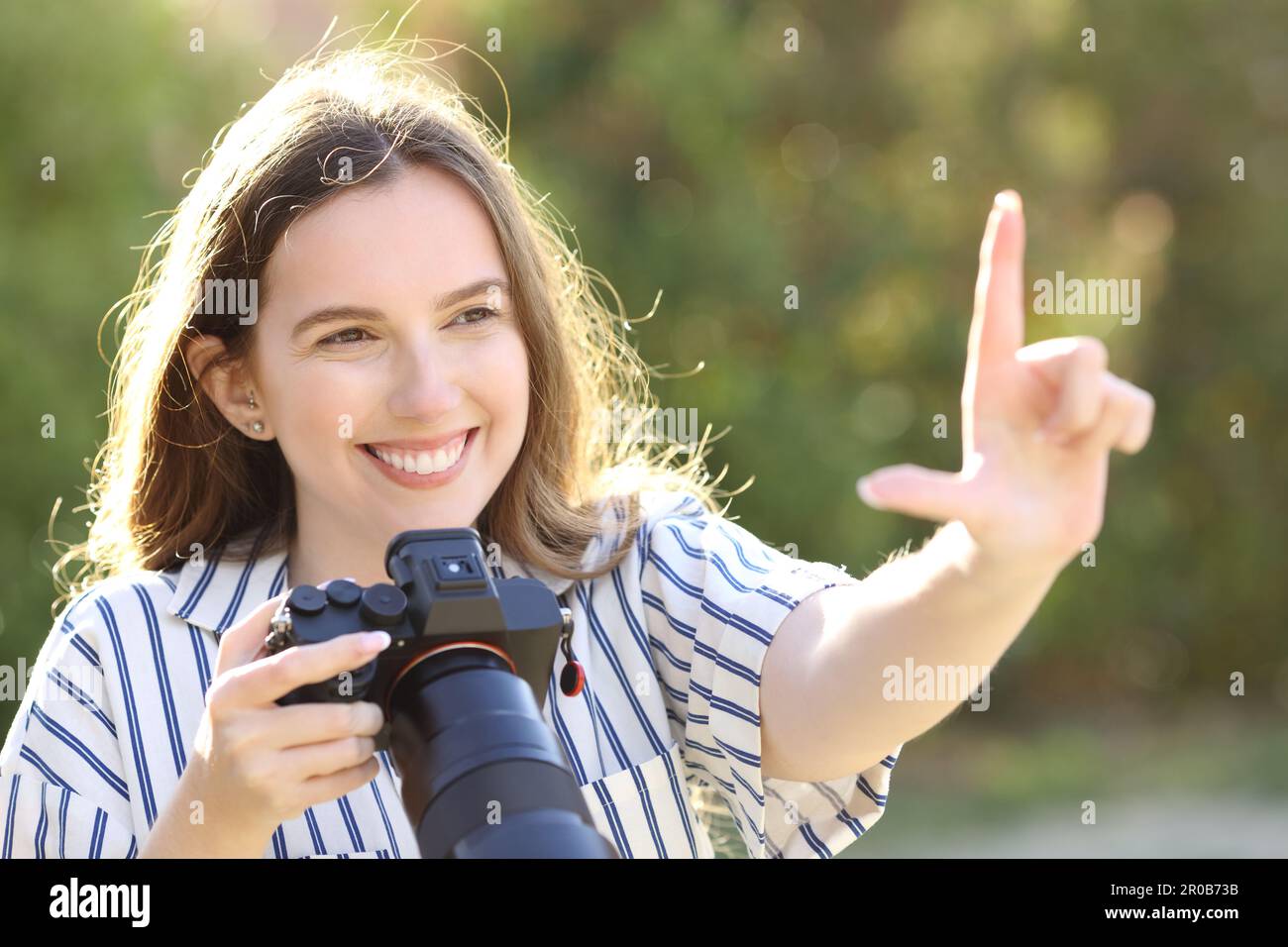 Happy photographer calculating frame with her hand holding mirrorless camera Stock Photo