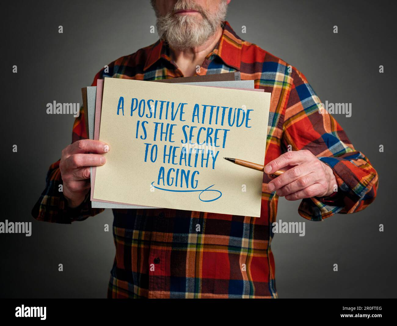 A positive attitude is the secret to healthy aging - inspirational note held by a senior man Stock Photo