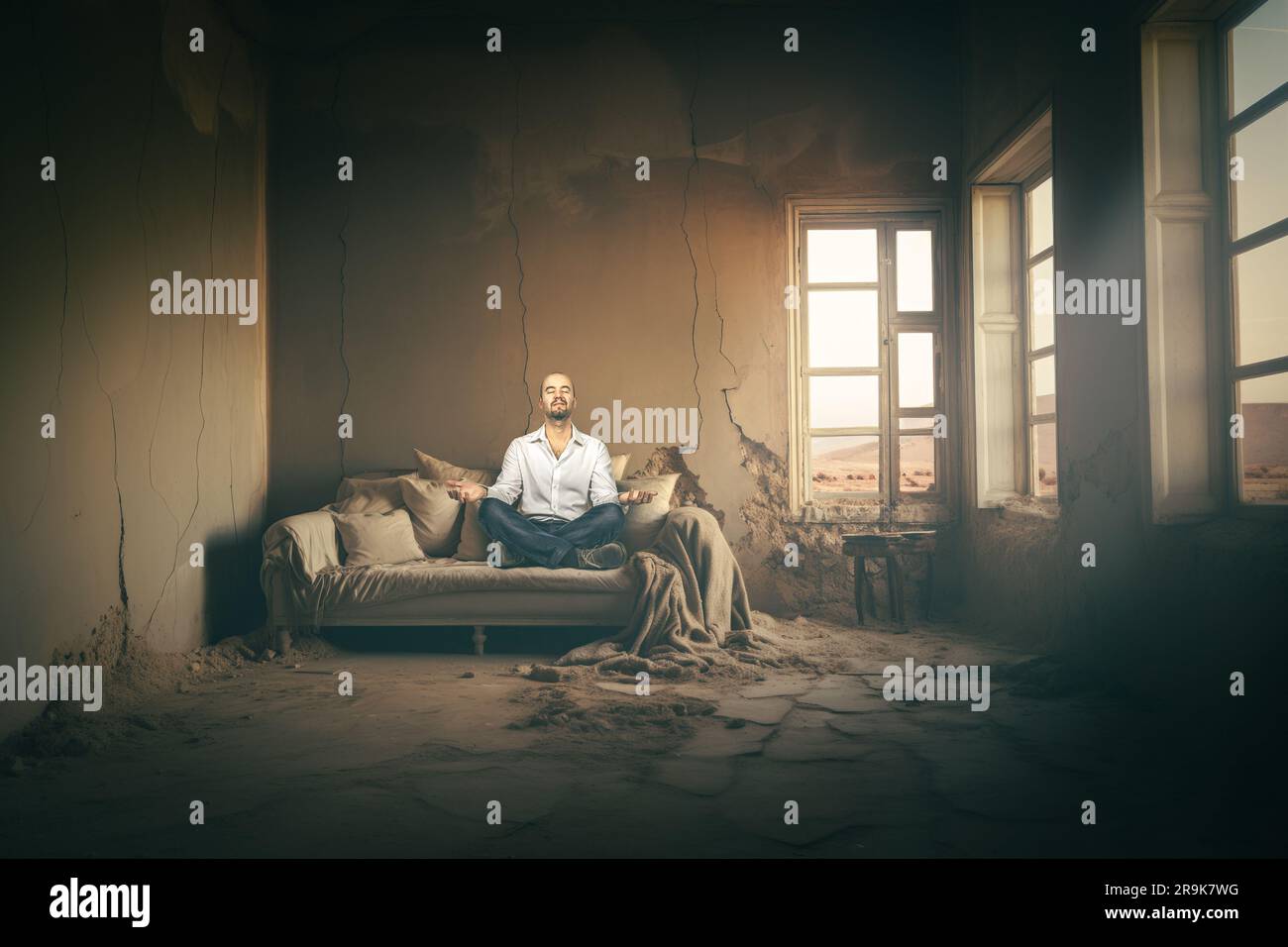 man meditating in a dilapidated house Stock Photo