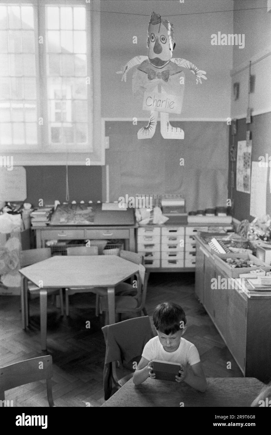 Naughty child at village primary school 1970s UK. This young boy had been bad and was made to stay in and punished. He had been a 'Proper Charlie'. A common expression at the time for someone who had been silly or stupid. He had to sit under a paper cut out figure of Charlie as punishment. Cheveley, Cambridgeshire, England 1978. HOMER SYKES Stock Photo