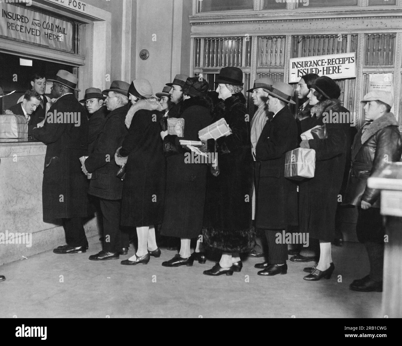 New York, New York:   December 22, 1927 People lined up at the parcel post window at the General Post Office in N.Y. to mail their Christmas packages. Stock Photo