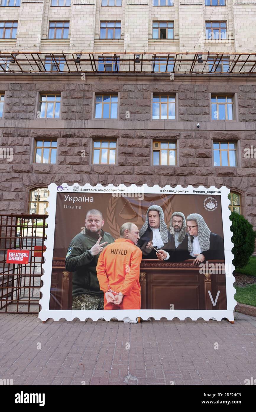 In the streets of Kyiv, a giant stamp depicts Putin's trial before the International Criminal Court. He is led to the judges by Zaluzhnyi Stock Photo