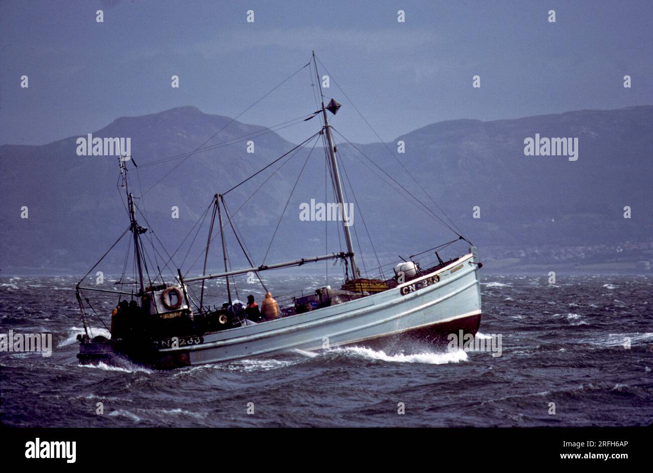 FISHING BOAT AT SEA IN BLEAK WEATHER MANY YEARS AGO Stock Photo