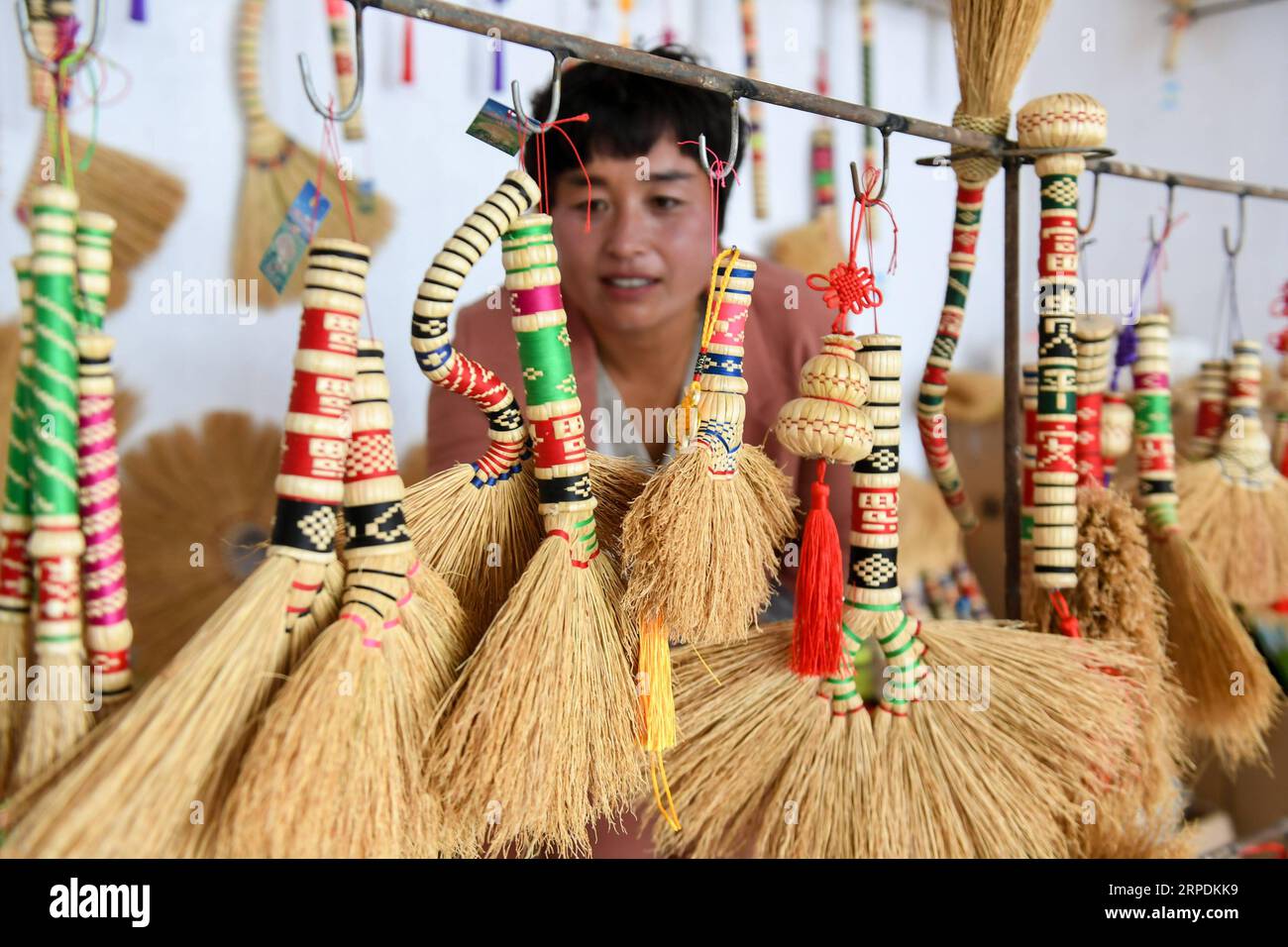 (190807) -- CHIFENG, Aug. 7, 2019 -- A woman views handmade brooms at an exhibition hall in Baiyingou Village of Lindong Township in Balin Left Banner of Chifeng City, north China s Inner Mongolia Autonomous Region, Aug. 5, 2019. Balin Left Banner has in recent years been committed to developing the comprehensive industrial chain of broom that involves planting, processing, product development, promotion and sales and brand building, as a way to help farmers boost their income. By the end of 2018, about 65,000 people had been involved in the broom industry, by which more than 6,000 people had Stock Photo