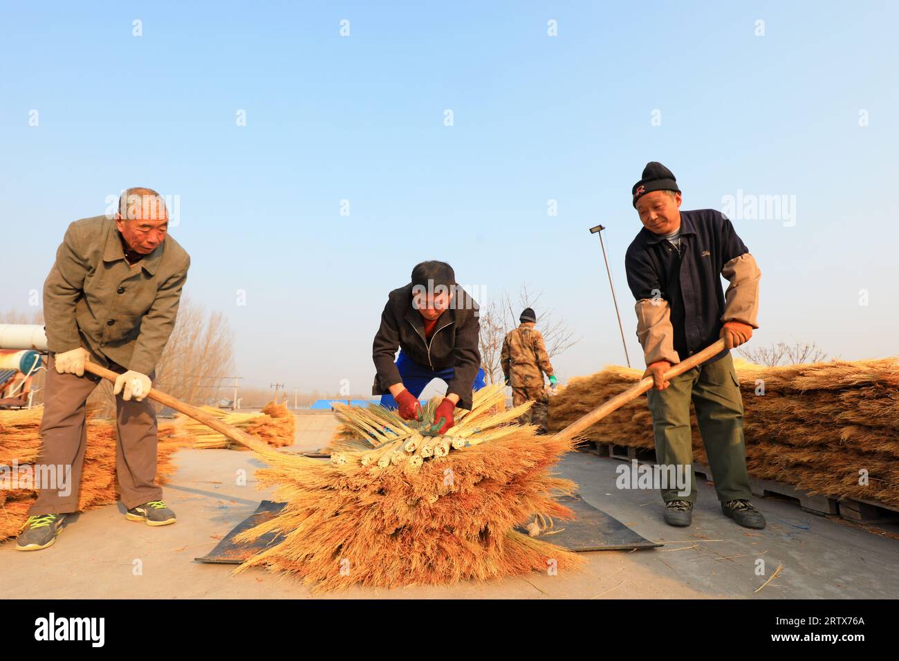 LUANNAN COUNTY, China - December 14, 2021: farmers pack brooms on the roof of a handmade workshop in North China Stock Photo