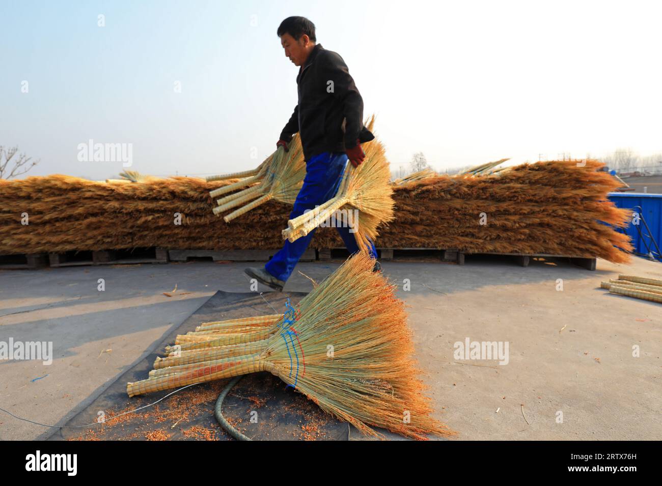 LUANNAN COUNTY, China - December 14, 2021: farmers pack brooms on the roof of a handmade workshop in North China Stock Photo