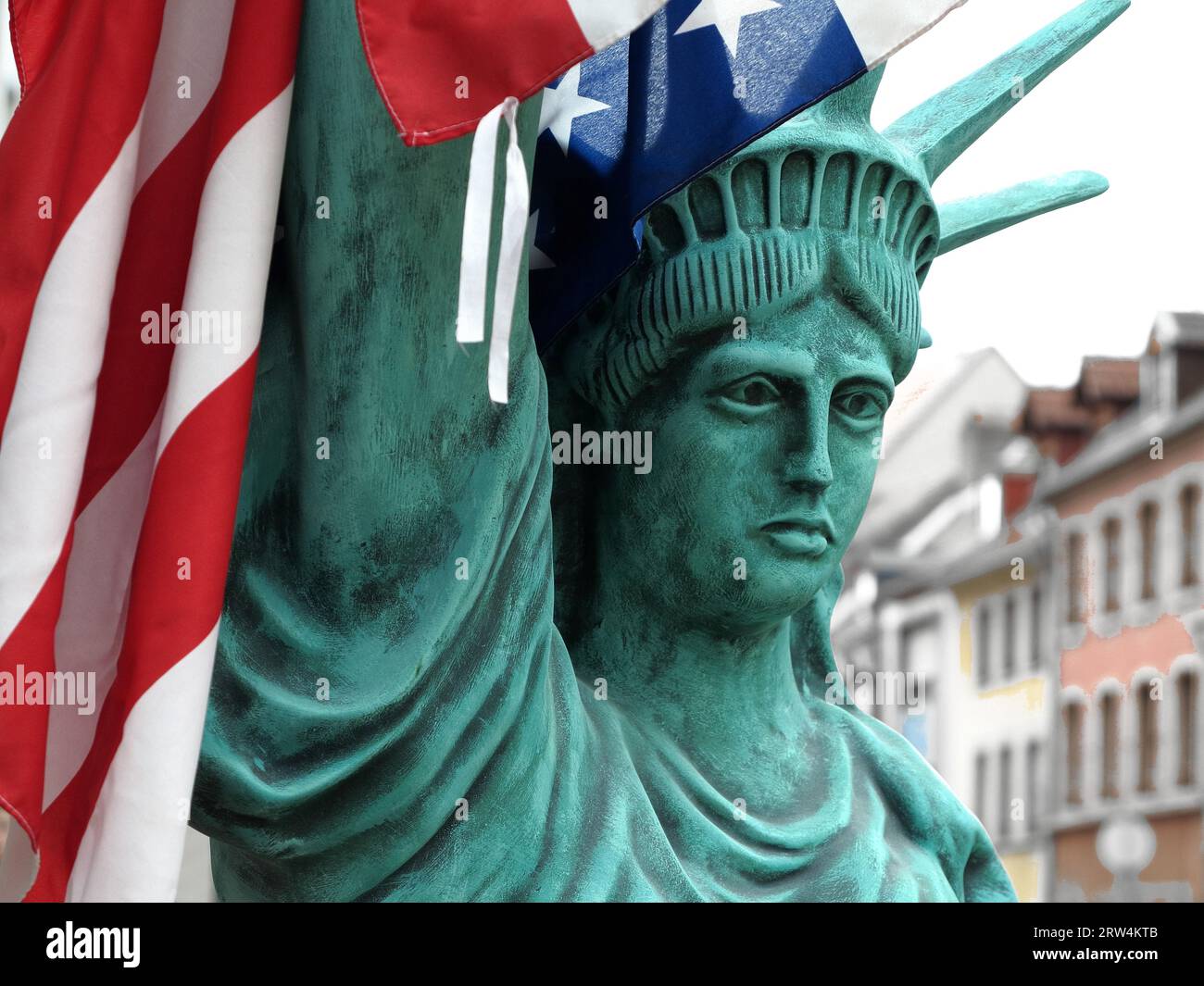 Figure of the Statue of Liberty with US flag, background houses, taken with depth of field Stock Photo