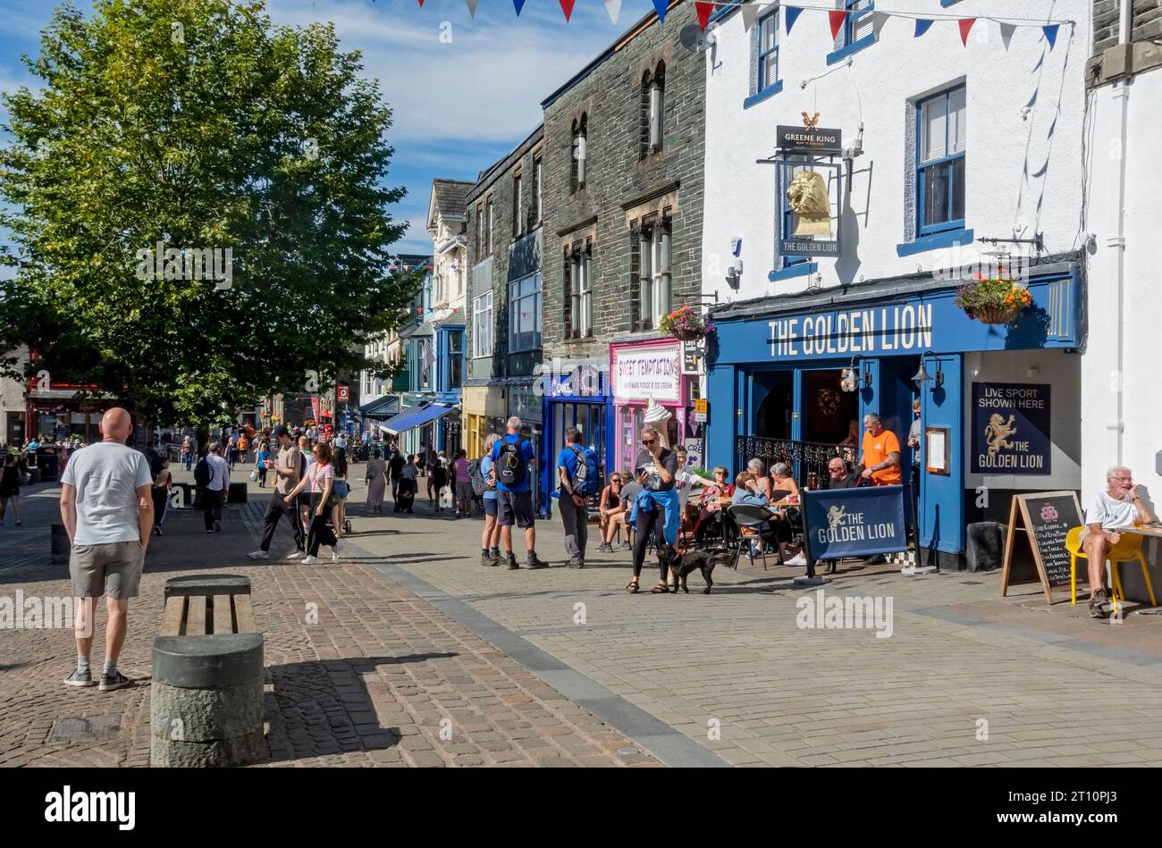 People tourists visitors and shops in the town centre street in summer Main Street Keswick Lake District Cumbria England UK Great Britain Stock Photo