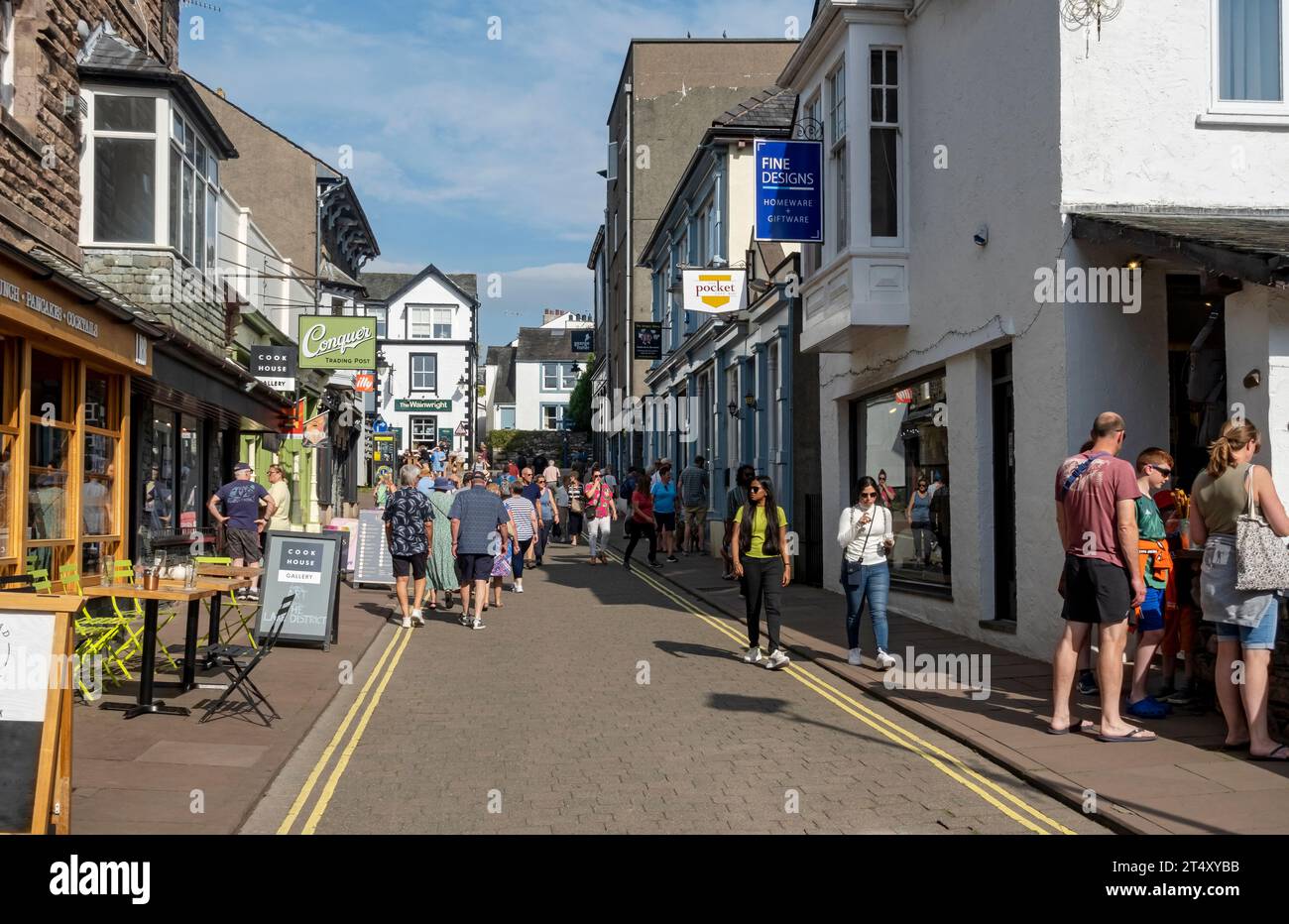 People tourists visitors walking in the busy town centre street shops in summer Lake Road Keswick Cumbria England UK United Kingdom GB Great Britain Stock Photo