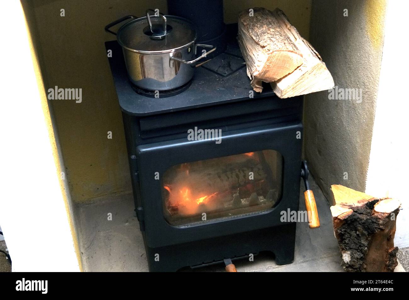 log burner stove with spare logs and a food  saucepan,uk november 2023 Stock Photo