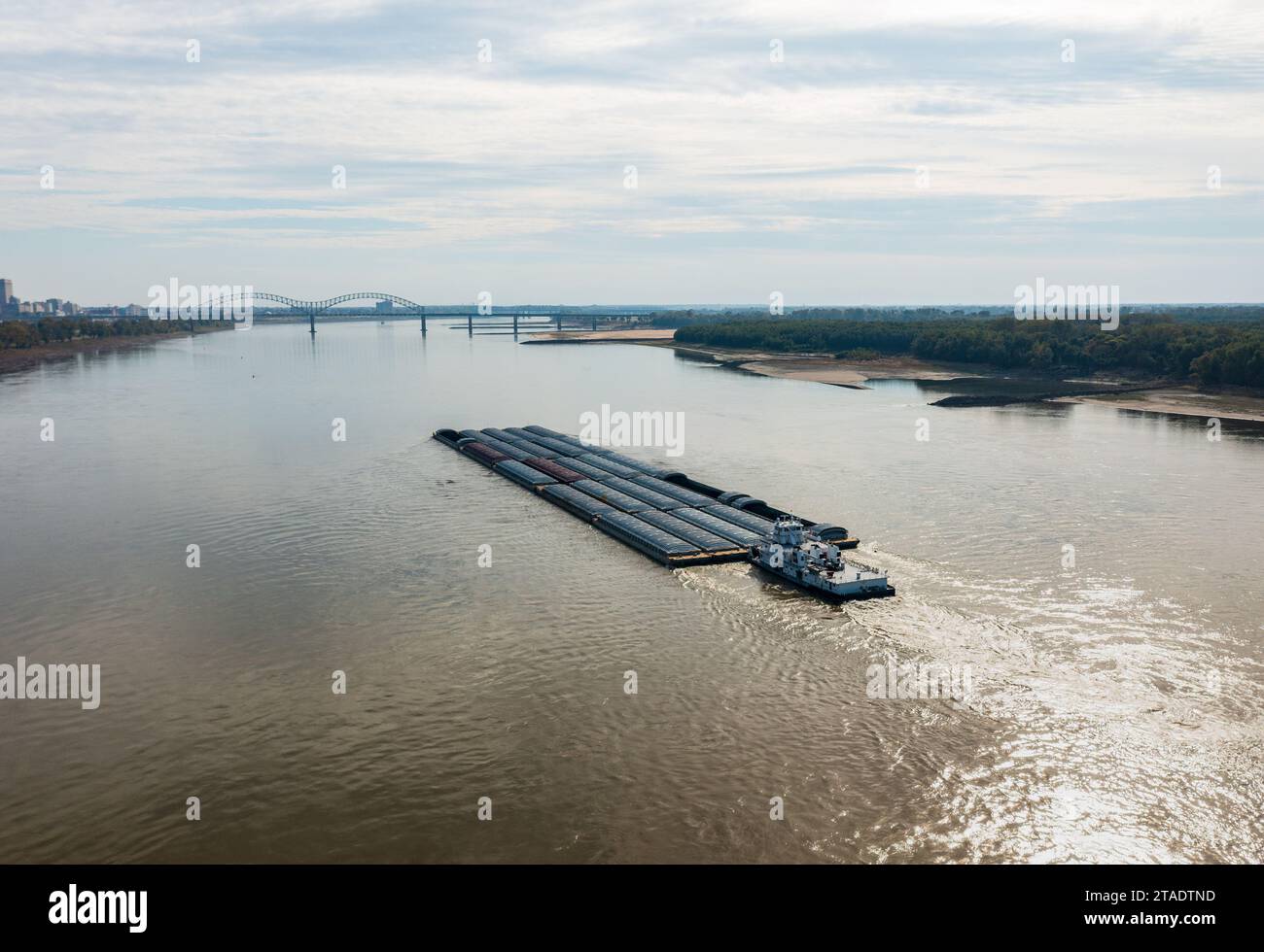 Extreme low water conditions on Mississippi river under Hernando de Soto bridge in Memphis TN as barge sails downstream Stock Photo