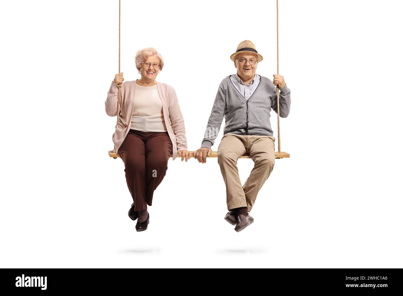 Elderly man and woman sitting on a wooden swing isolated on white background Stock Photo