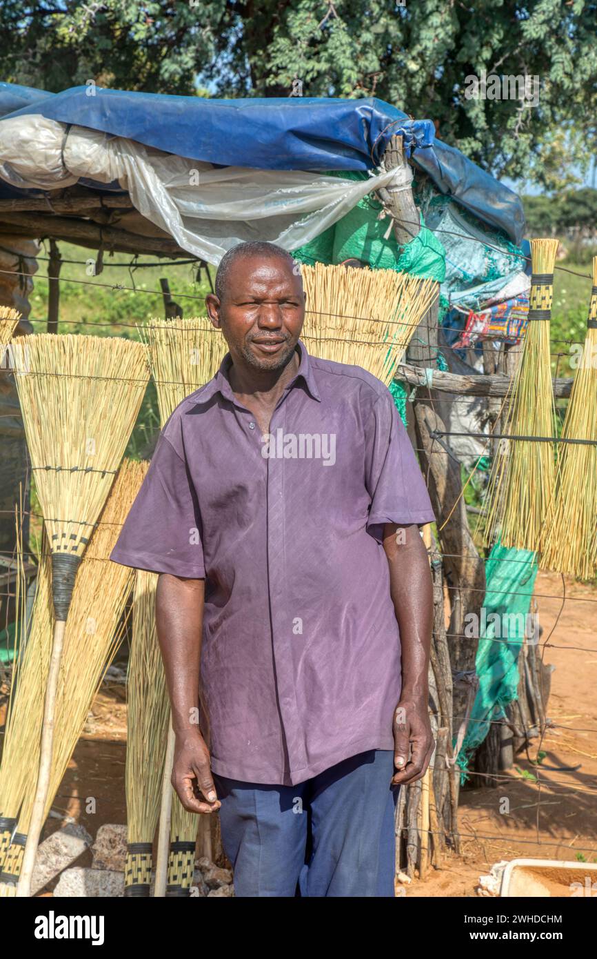 african old entrepreneur man making brooms, street vendor with a small stall at the side of the highway Stock Photo