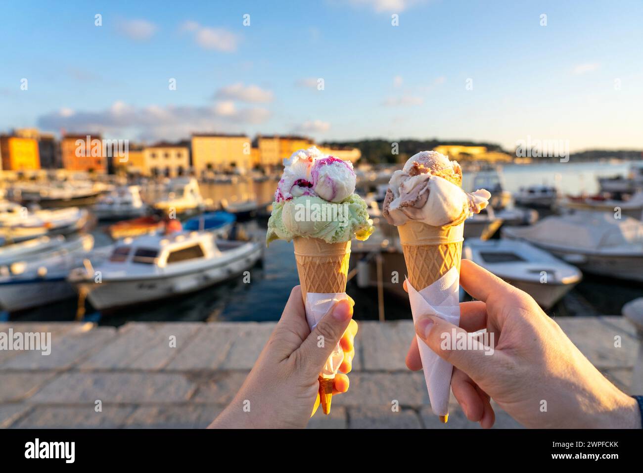 couple eating ice cream in Rovinj harbor with sunlight . Stock Photo