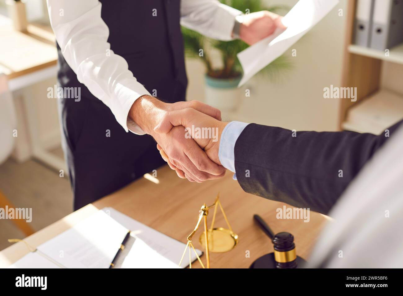 Male lawyer shaking hand with a man client standing at the desk on workplace in office. Stock Photo