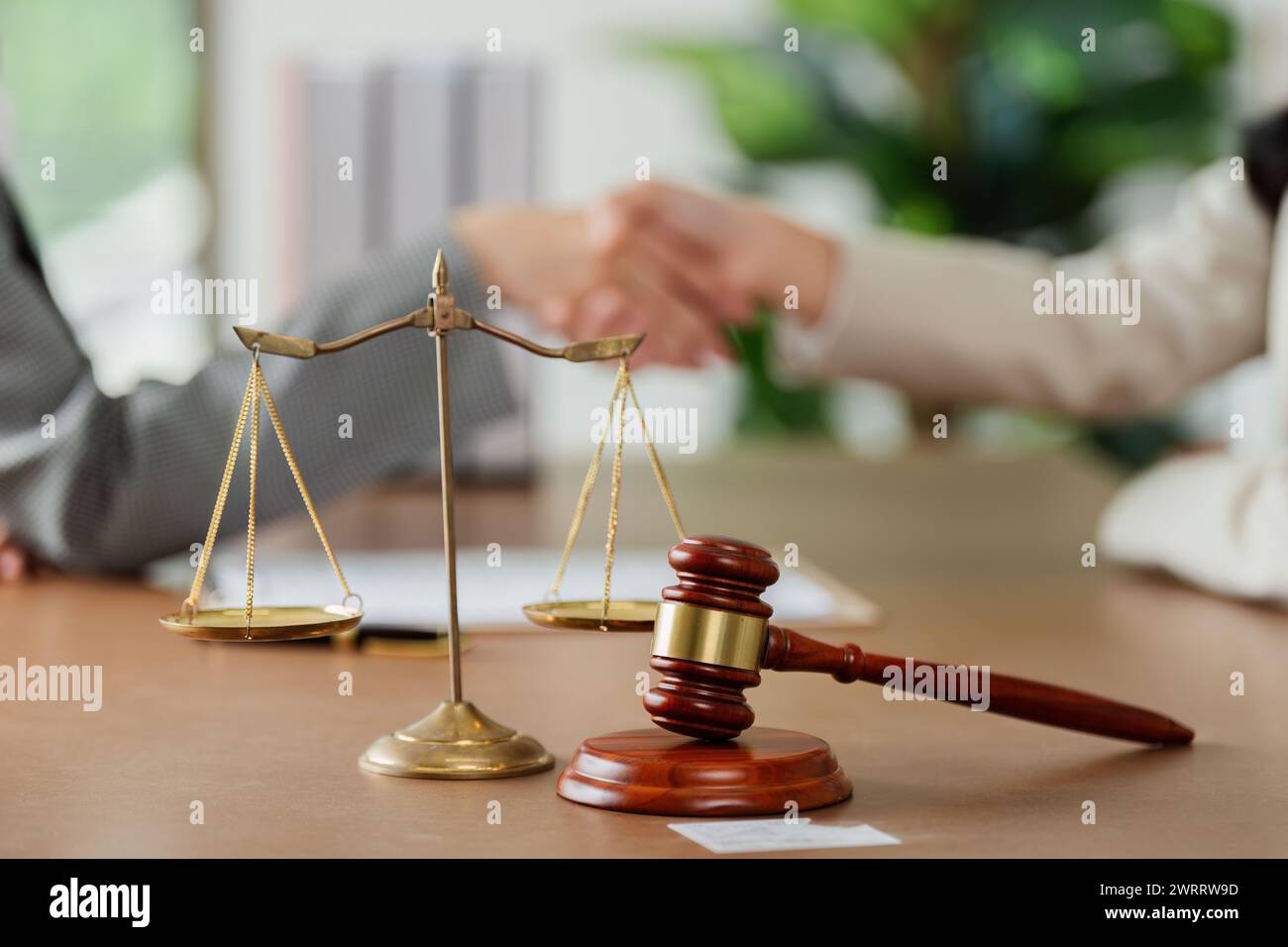 law and justice is represented by a mallet gavel of the judge, scales of justice, lawyer and client shaking hands Stock Photo