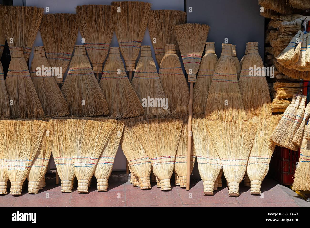 Handmade brooms lined up for sale on the street. Stock Photo