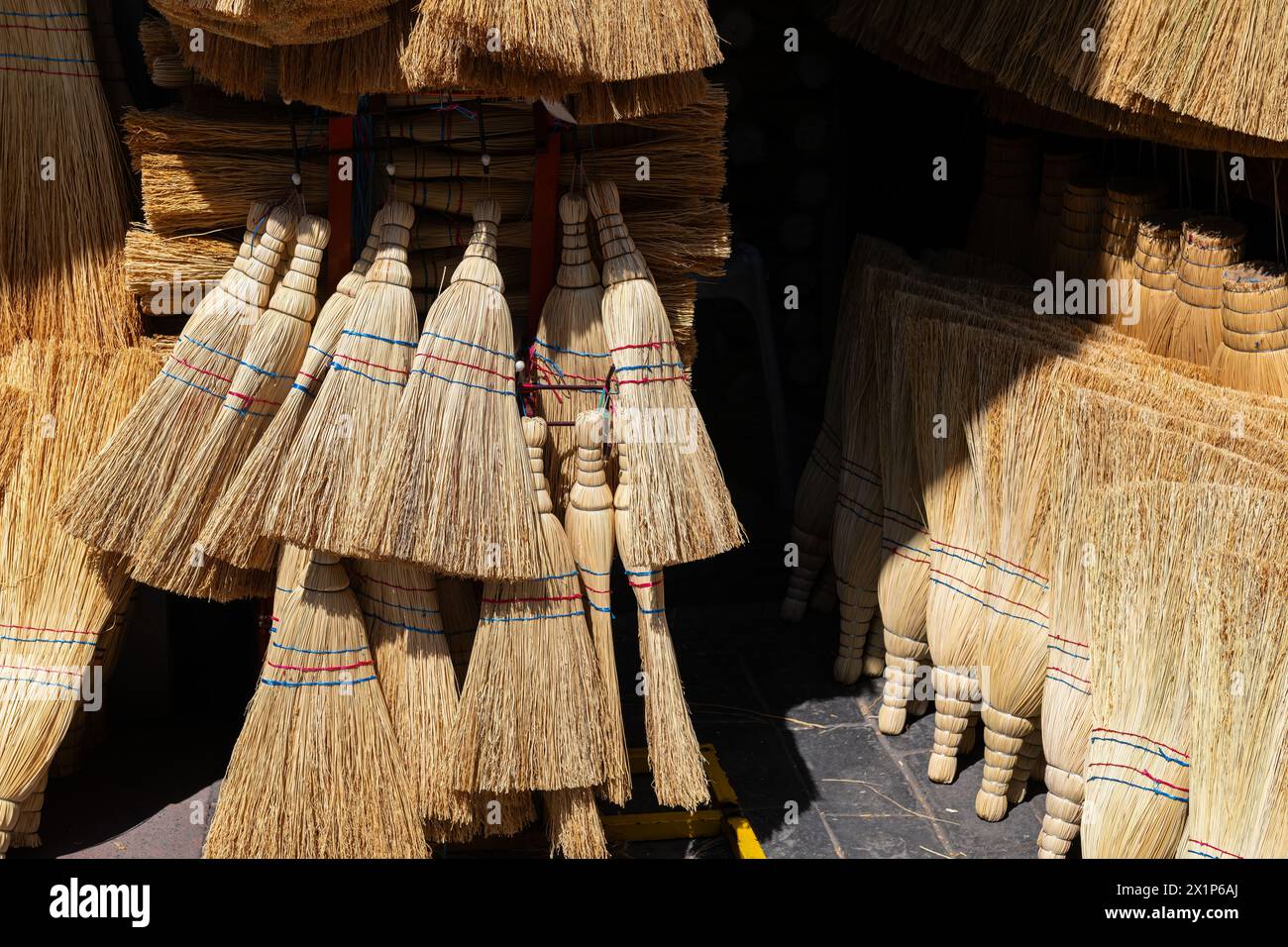 Handmade brooms lined up for sale on the street. Stock Photo