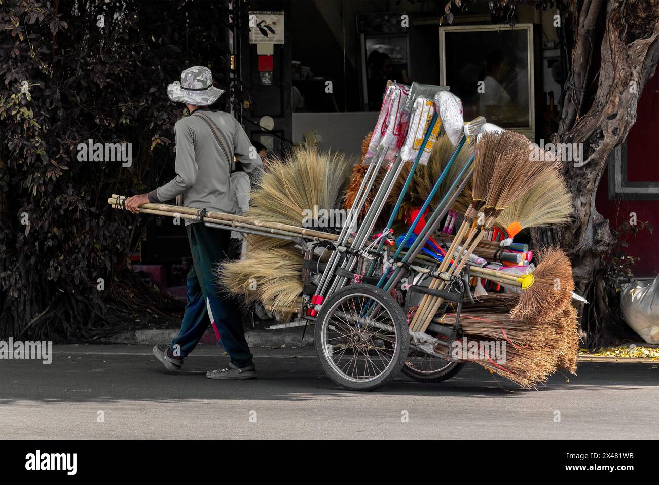 Bangkok, Thailand, January 18, 2023: The daily life of a peddling man with his pulled two-wheeled cart selling cleaning tools. Stock Photo