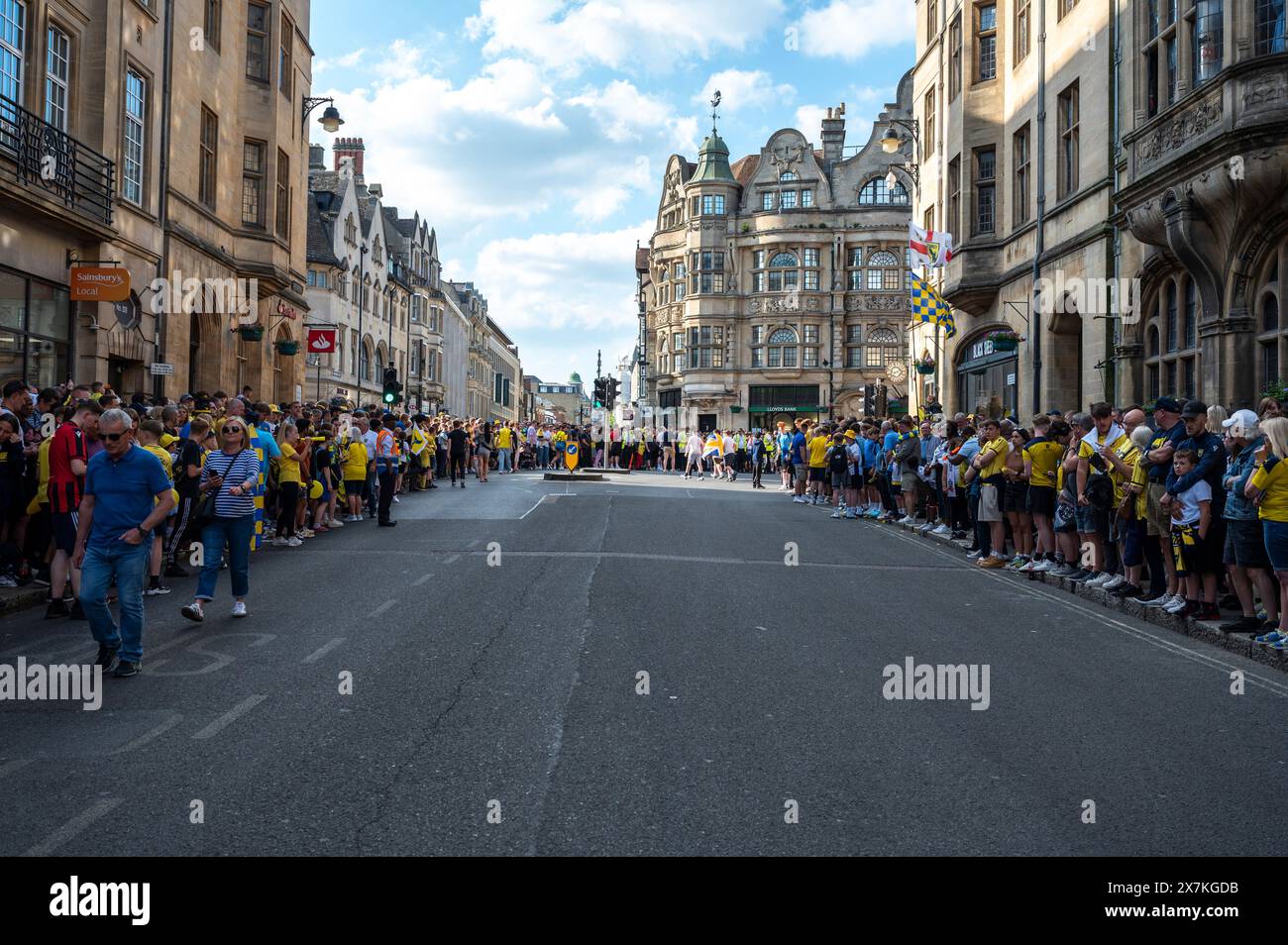 Thousands of Oxford United fans lined the city centre of Oxford to celebrate the promotion of Oxford United to the EFL Championship after beating the Bolton Wanders in the League One playoff at Wembley on the weekend. The crowds, decked out in yellow, cheered loudly and let off yellow flares as the open-top bus carrying the team and staff slowly moved along the High Street to the Oxford City Town Hall, where they attended an invite-only civic reception. The Oxford United flag flew over the Oxford City Council building in celebration. Stock Photo