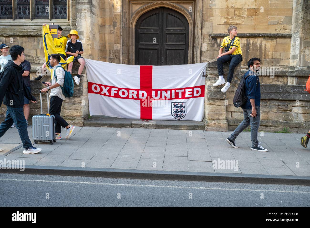 Thousands of Oxford United fans lined the city centre of Oxford to celebrate the promotion of Oxford United to the EFL Championship after beating the Bolton Wanders in the League One playoff at Wembley on the weekend. The crowds, decked out in yellow, cheered loudly and let off yellow flares as the open-top bus carrying the team and staff slowly moved along the High Street to the Oxford City Town Hall, where they attended an invite-only civic reception. The Oxford United flag flew over the Oxford City Council building in celebration. Stock Photo