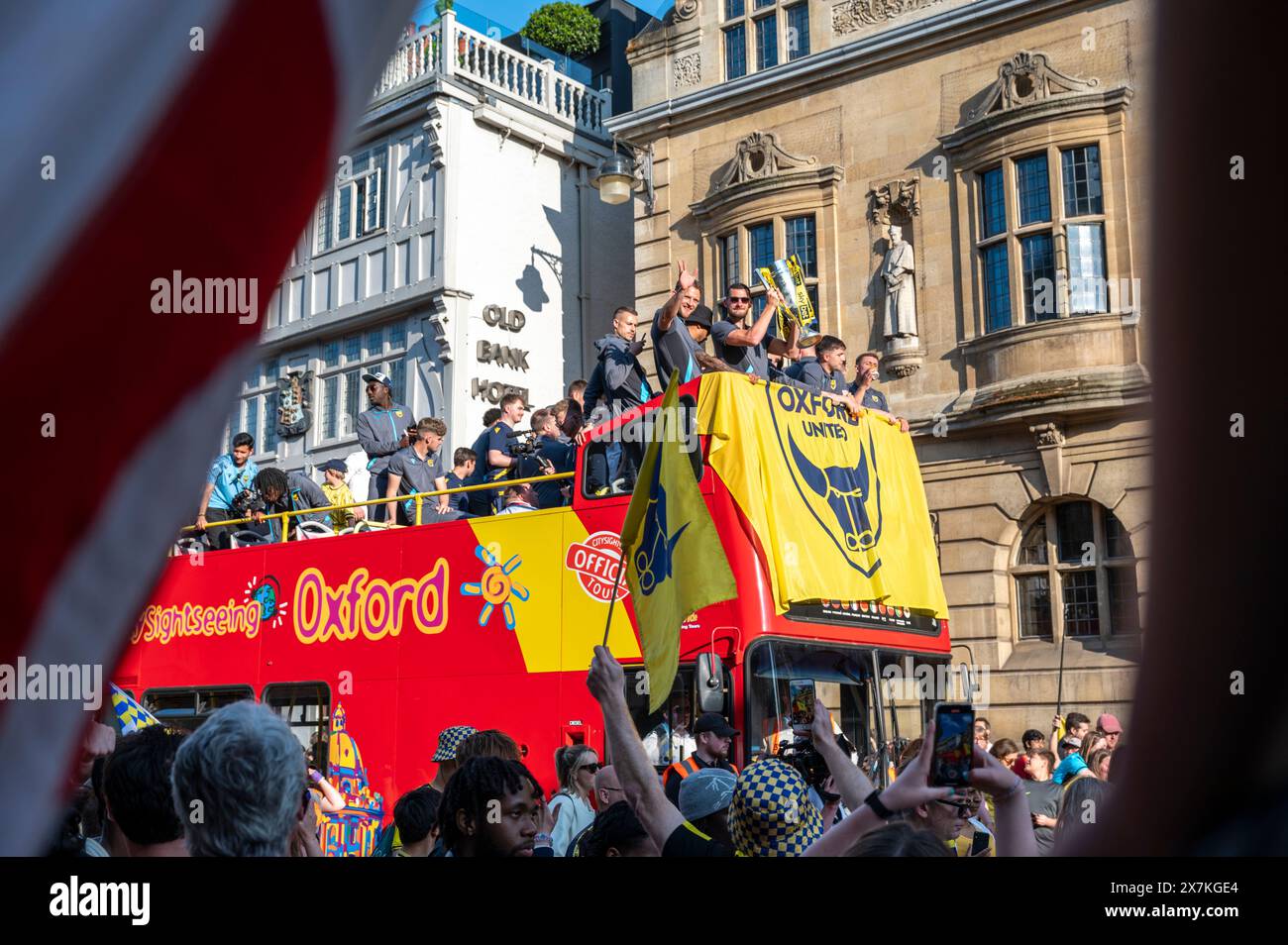 Thousands of Oxford United fans lined the city centre of Oxford to celebrate the promotion of Oxford United to the EFL Championship after beating the Bolton Wanders in the League One playoff at Wembley on the weekend. The crowds, decked out in yellow, cheered loudly and let off yellow flares as the open-top bus carrying the team and staff slowly moved along the High Street to the Oxford City Town Hall, where they attended an invite-only civic reception. The Oxford United flag flew over the Oxford City Council building in celebration. Stock Photo