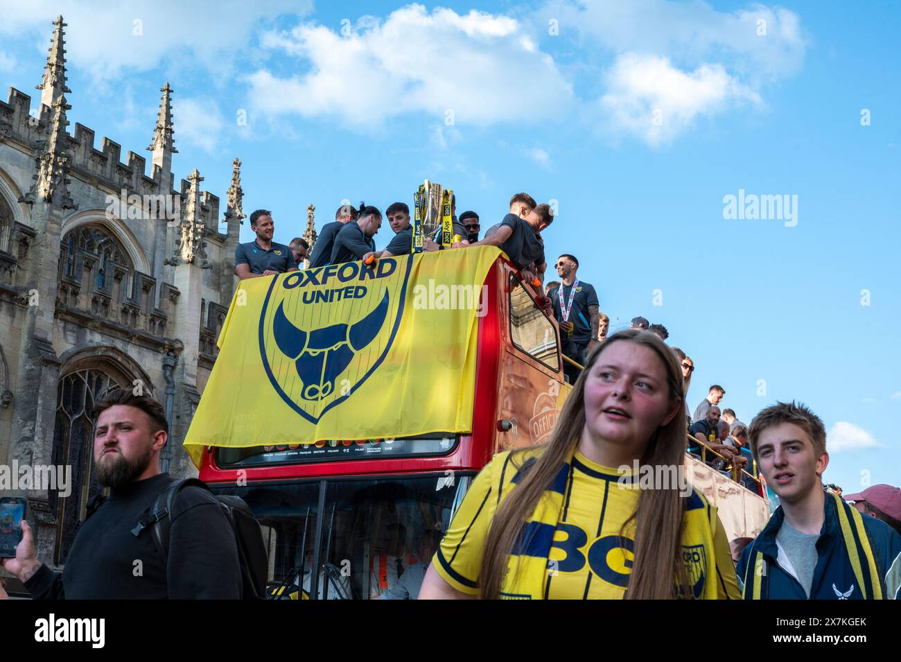 Thousands of Oxford United fans lined the city centre of Oxford to celebrate the promotion of Oxford United to the EFL Championship after beating the Bolton Wanders in the League One playoff at Wembley on the weekend. The crowds, decked out in yellow, cheered loudly and let off yellow flares as the open-top bus carrying the team and staff slowly moved along the High Street to the Oxford City Town Hall, where they attended an invite-only civic reception. The Oxford United flag flew over the Oxford City Council building in celebration. Stock Photo